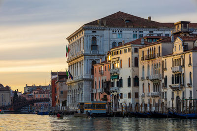 Canal amidst buildings in city against sky