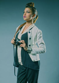 Young woman looking away while standing against blue background