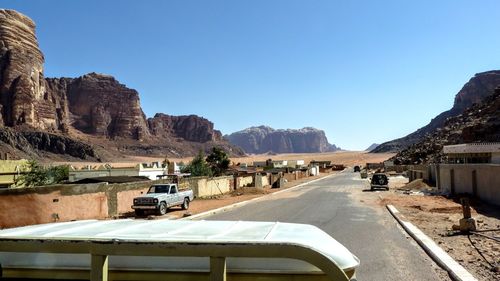 Road leading towards mountains against clear blue sky