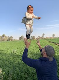 Happy father with his little daughter against sky