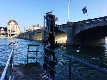 Bridge over river in city against clear blue sky