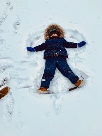 High angle view of boy lying on snowy field