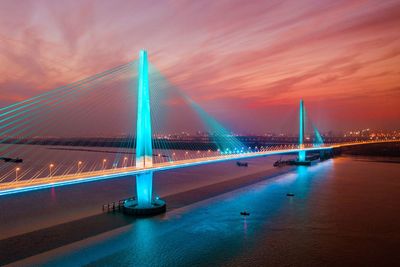 Illuminated bridge over river against sky