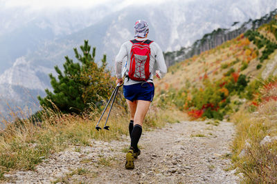 Rear view of man walking on field against mountain