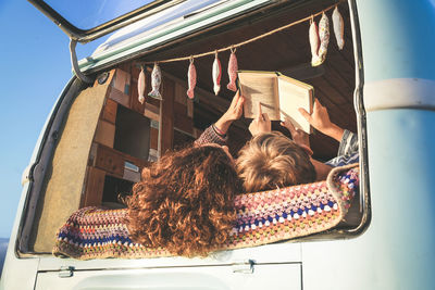 Low angle view of mother and son reading book in car