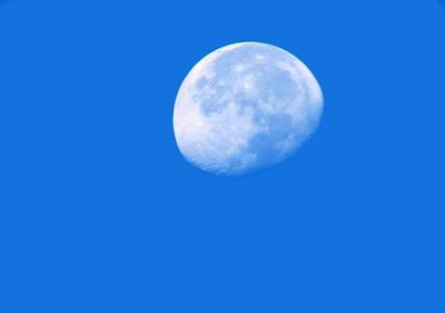 Low angle view of moon against blue sky