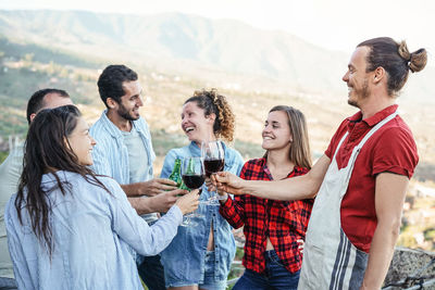 People toasting glasses and bottles against sky