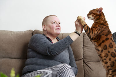 Woman playing with cat on sofa