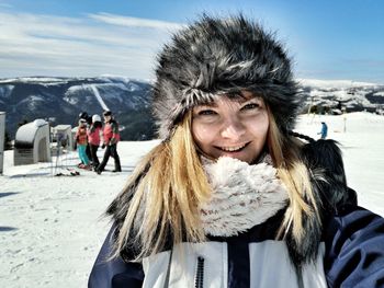 Portrait of smiling young woman standing on snow covered mountain