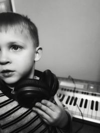 Close-up of boy looking away sitting by piano at home