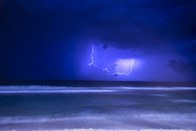Lightning over sea against sky at night