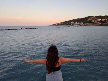 Rear view of woman standing on sea against sky