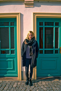 Portrait of a young woman standing against building