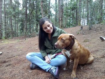 Smiling woman with dog in forest