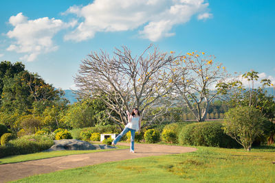 Rear view of woman walking on field against sky