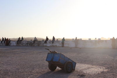 People sitting on retaining wall against clear sky