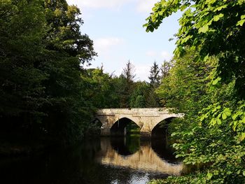 Arch bridge over river against sky