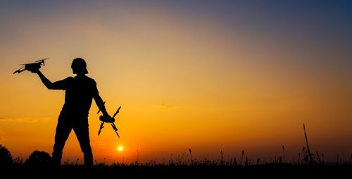 Silhouette man standing on land against sky during sunset