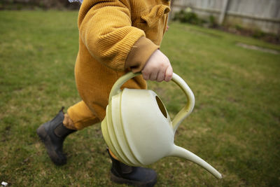 Midsection of boy holding watering can at lawn