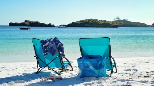 Chairs on beach against clear blue sky