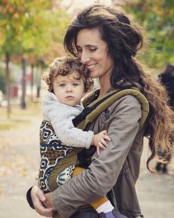 Portrait of happy mother and daughter against trees