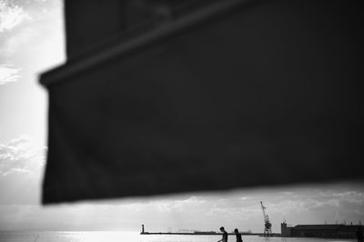 Low angle view of silhouette building by sea against sky