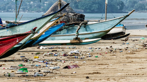 Fishing boats moored by garbage at beach