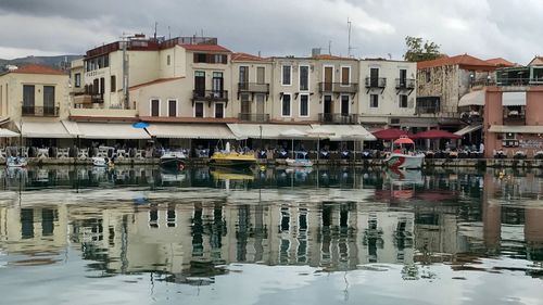 Sailboats in city by buildings against sky