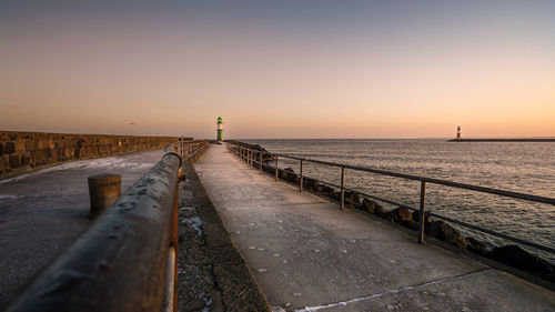 Pier over sea against clear sky during sunset