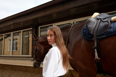 Portrait of young woman standing against building
