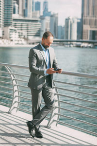 Full length of man standing at railing against buildings in city