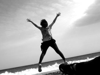 Woman with arms raised standing against sky