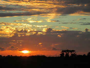 Scenic view of silhouette landscape against dramatic sky during sunset