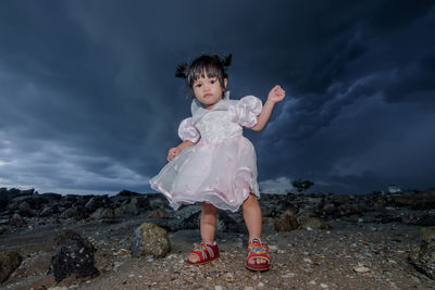 Girl standing on rock against sky