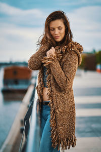 Beautiful woman with hand in hair standing by railing