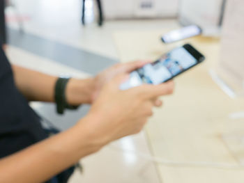 Midsection of man using mobile phone on table