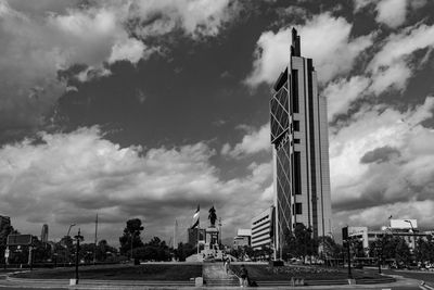 Statue in city against cloudy sky