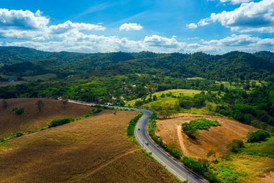 Scenic view of road amidst field against sky