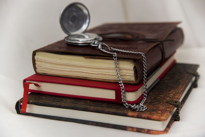 High angle view of pocket watch over books stack on table