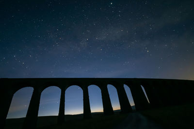 Low angle view of viaduct against milky way