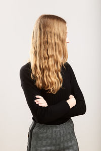 Teenage girl with blond hair standing against white background