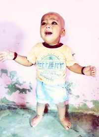 Cute boy looking away while standing against wall