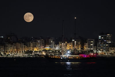 Boats moored at harbor at night