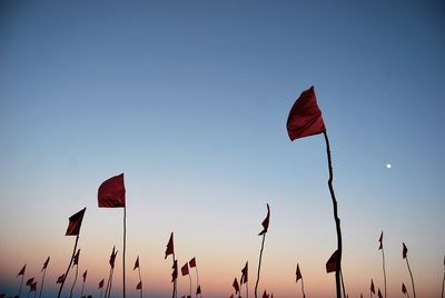 Low angle view of red flags waving against clear sky at dusk