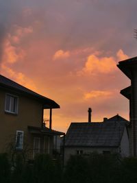 Houses and silhouette buildings against sky during sunset