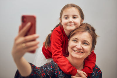 Mother with her little daughter making video call using mobile phone. keeping distance