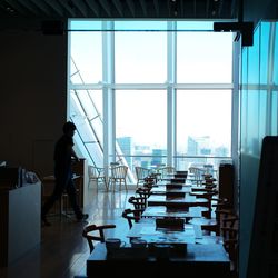 Side view of man standing by glass window