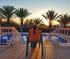 Rear view of man sitting in swimming pool against sky