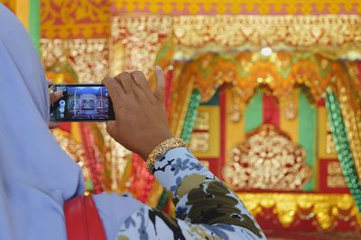 Cropped hand of woman photographing at temple