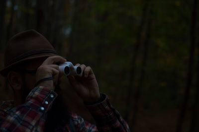 Close-up of man looking through binoculars in forest